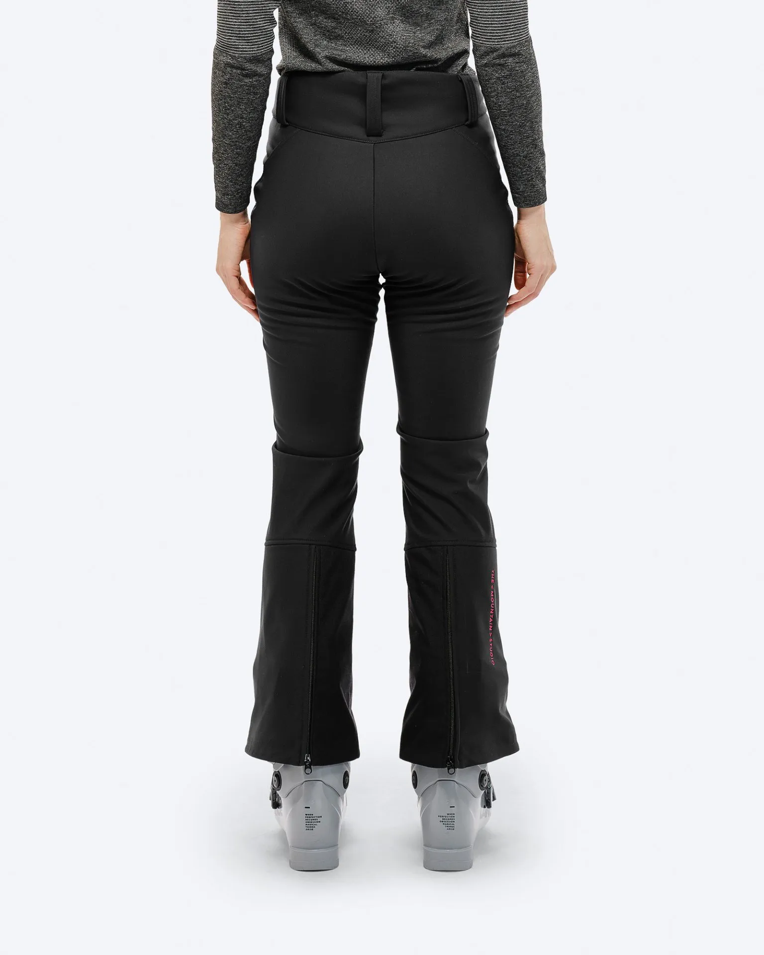 Rückansicht: Schwarze P-4 W 2L Stretch Ski Pants mit Skischuhen und pinkem Logo am Beinabschluss.