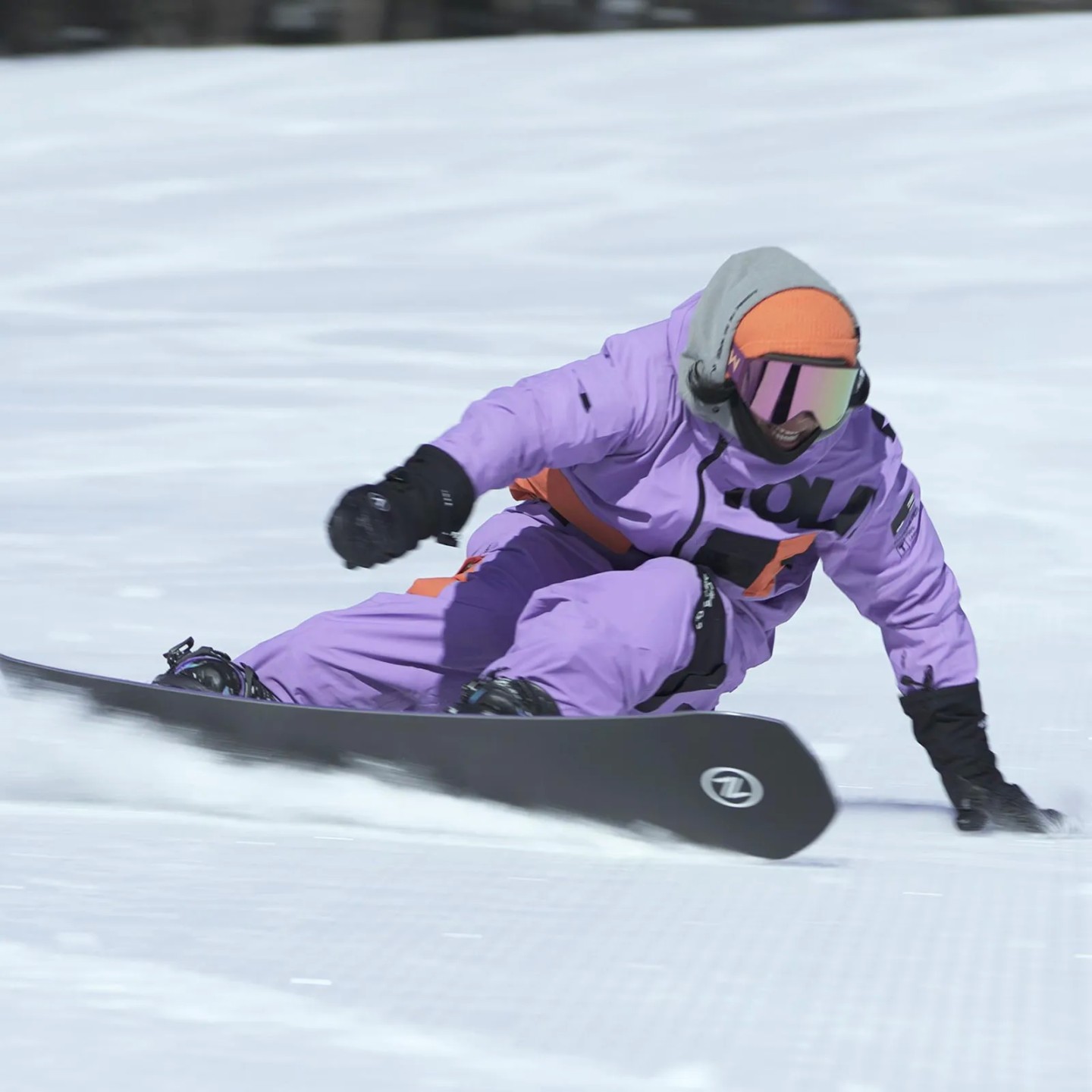 Snowboarder im lila Anzug Snowboarder in lila Anzug carvt auf dem Nidecker Blade Plus Snowboard im Schnee.