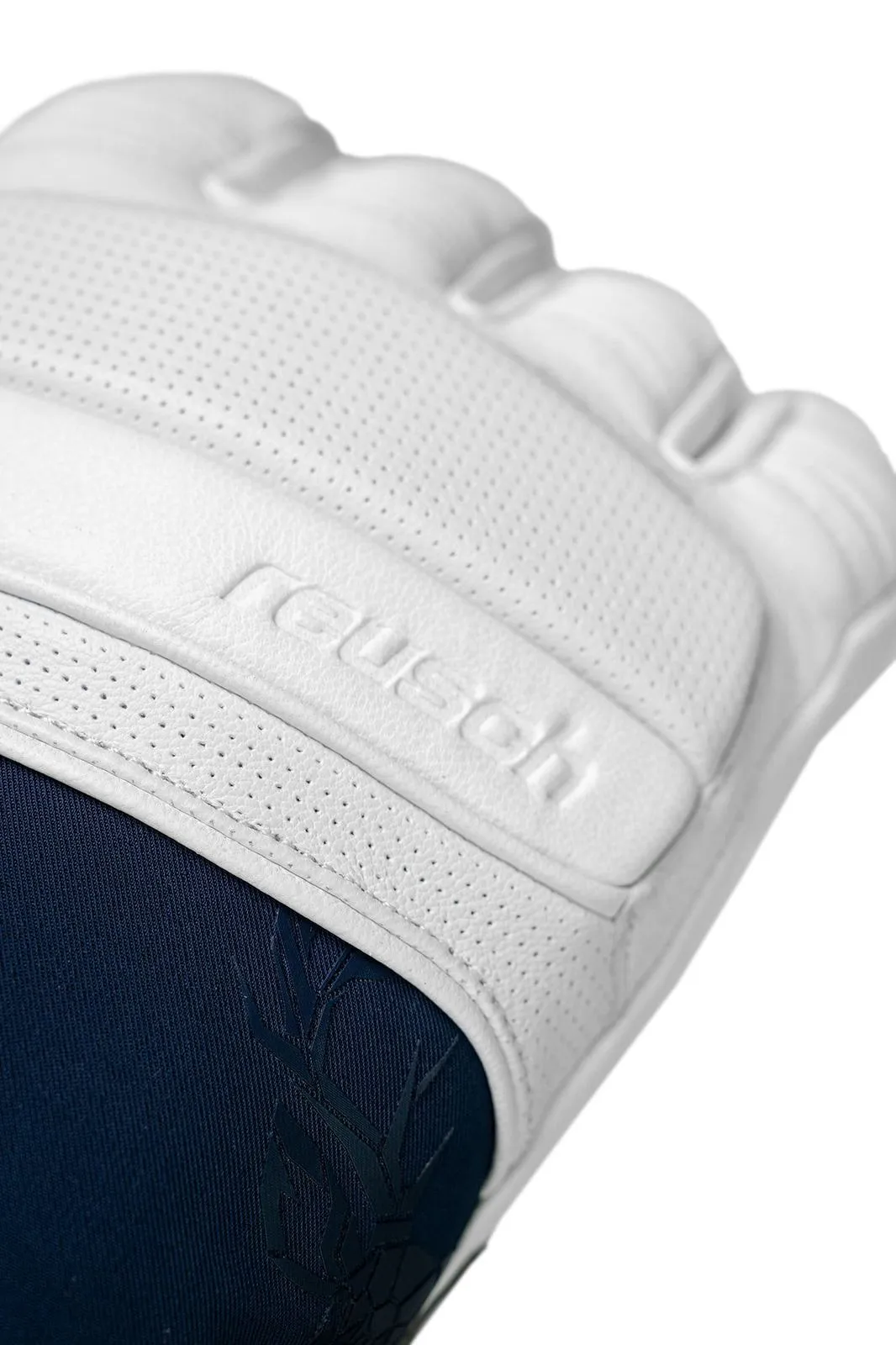 Close-up of a white goalkeeper glove with "Reusch" logo and blue fabric underneath. The surface has small holes.
