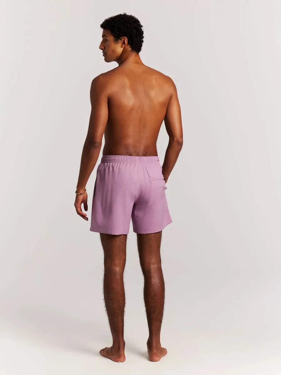 A man from behind, barefoot, wearing mauve Protest Daviey beach shorts against a light background.