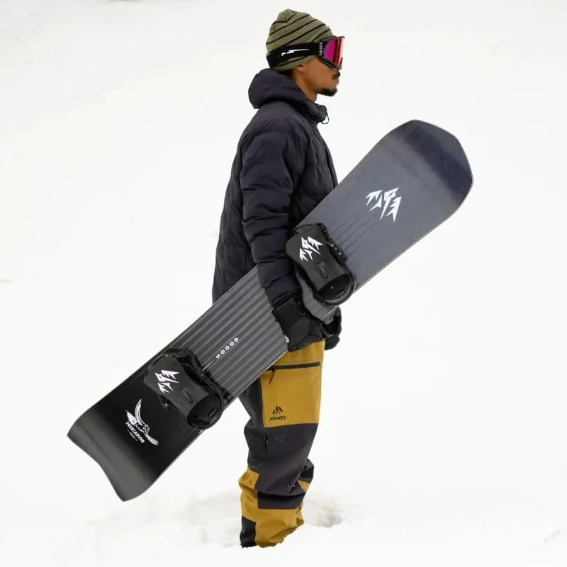 Person hält Freecarver 9000s Snowboard im Schnee, trägt Mütze und Skibrille.
