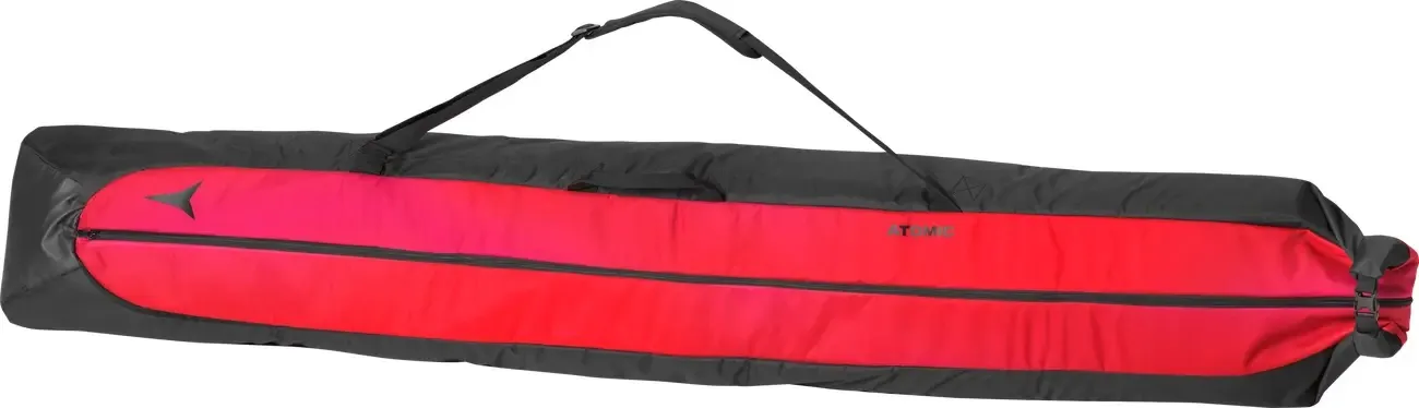 Un sac à skis est noir avec une large bande centrale rouge et une fermeture éclair. Une sangle est fixée en haut.