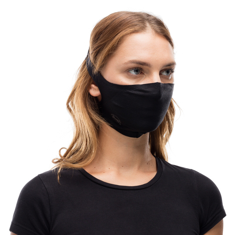 Junge Frau trägt eine schwarze Buff Filter Maske. Die Maske ist um den Kopf befestigt.
