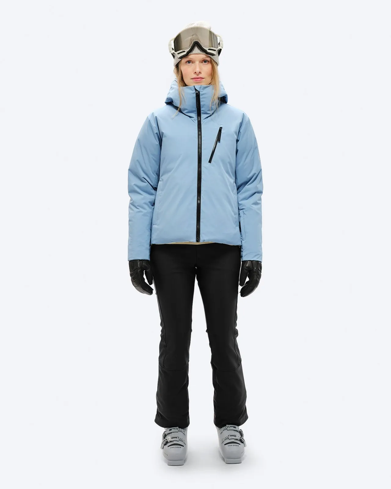 Person with ski goggles, down jacket in "Castle Wall", black trousers and gloves, as well as ski boots.