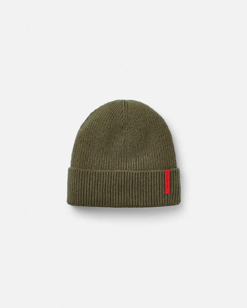 Grüne C-8 Cashmere Mix Rib Beanie mit rotem, vertikalem Logo-Etikett, isoliert auf weißem Hintergrund.