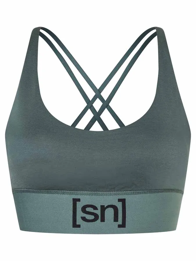 Grüner Super.Natural Sport BH mit gekreuzten Trägern und dem "[sn]" Logo am unteren Bund.