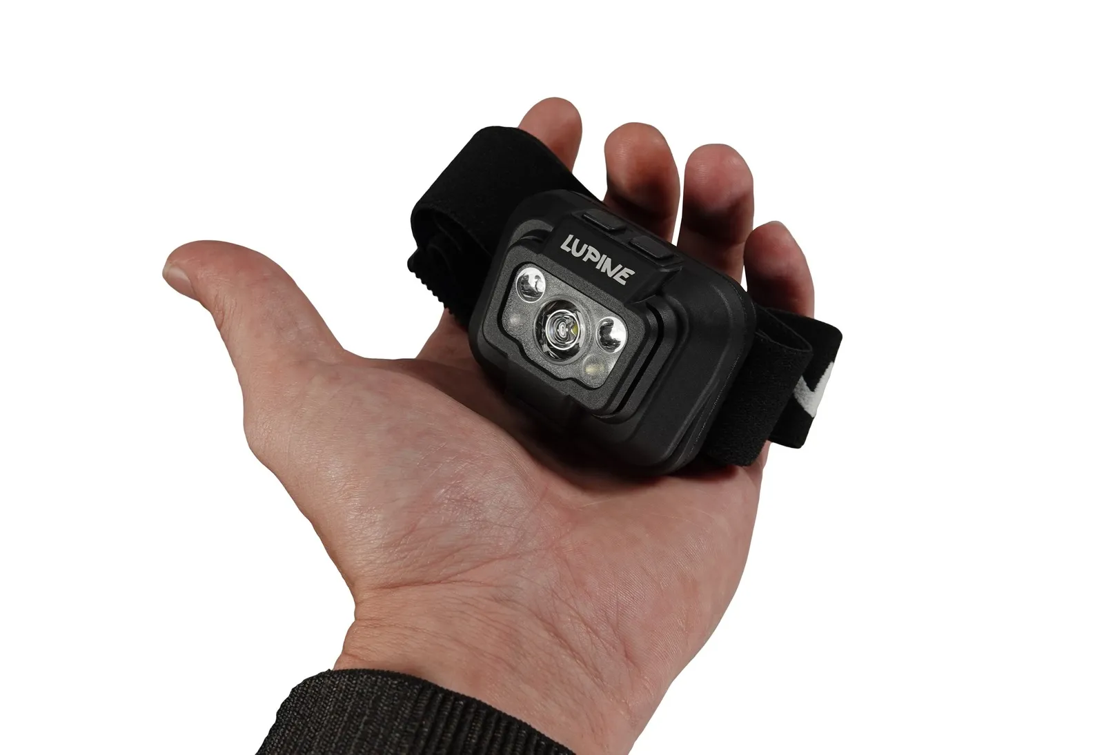 La main tient une lampe frontale Penta noire avec bandeau. La lampe est équipée de plusieurs LED et de deux boutons.