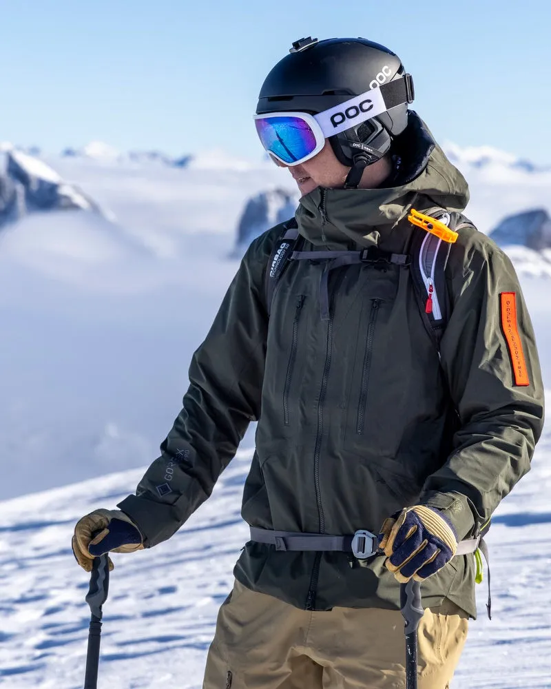 Skier in a green Z-2 HD GORE-TEX Pro jacket against a snowy mountain backdrop.