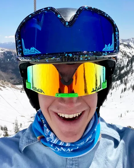 Ritratto di una persona sorridente che indossa un casco da sci e occhiali da sole Boomslang Polarised Double Wide verde neon.