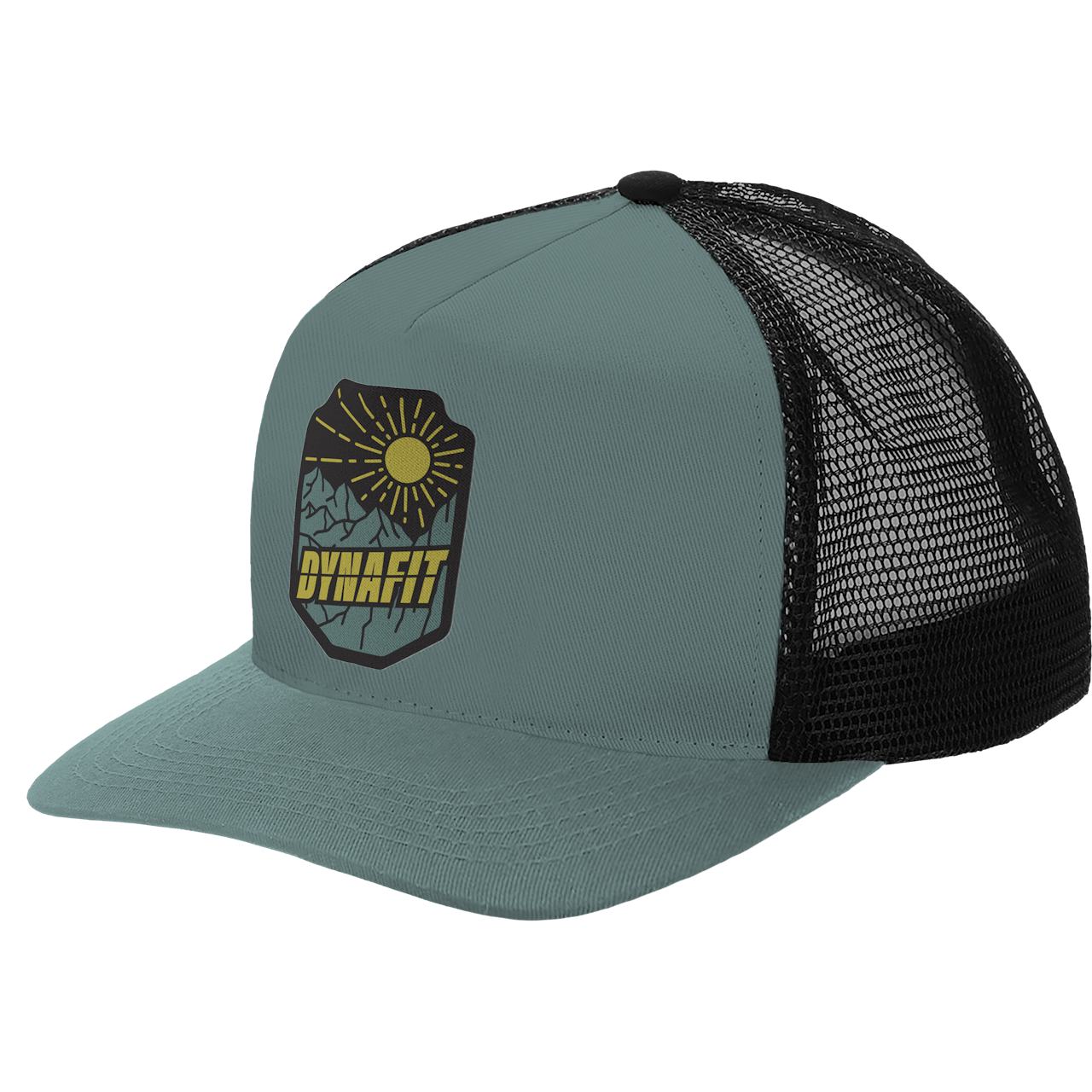 Hellgraue Trucker Cap mit schwarzem Netzteil und Dynafit Patch mit Bergen und Sonne.