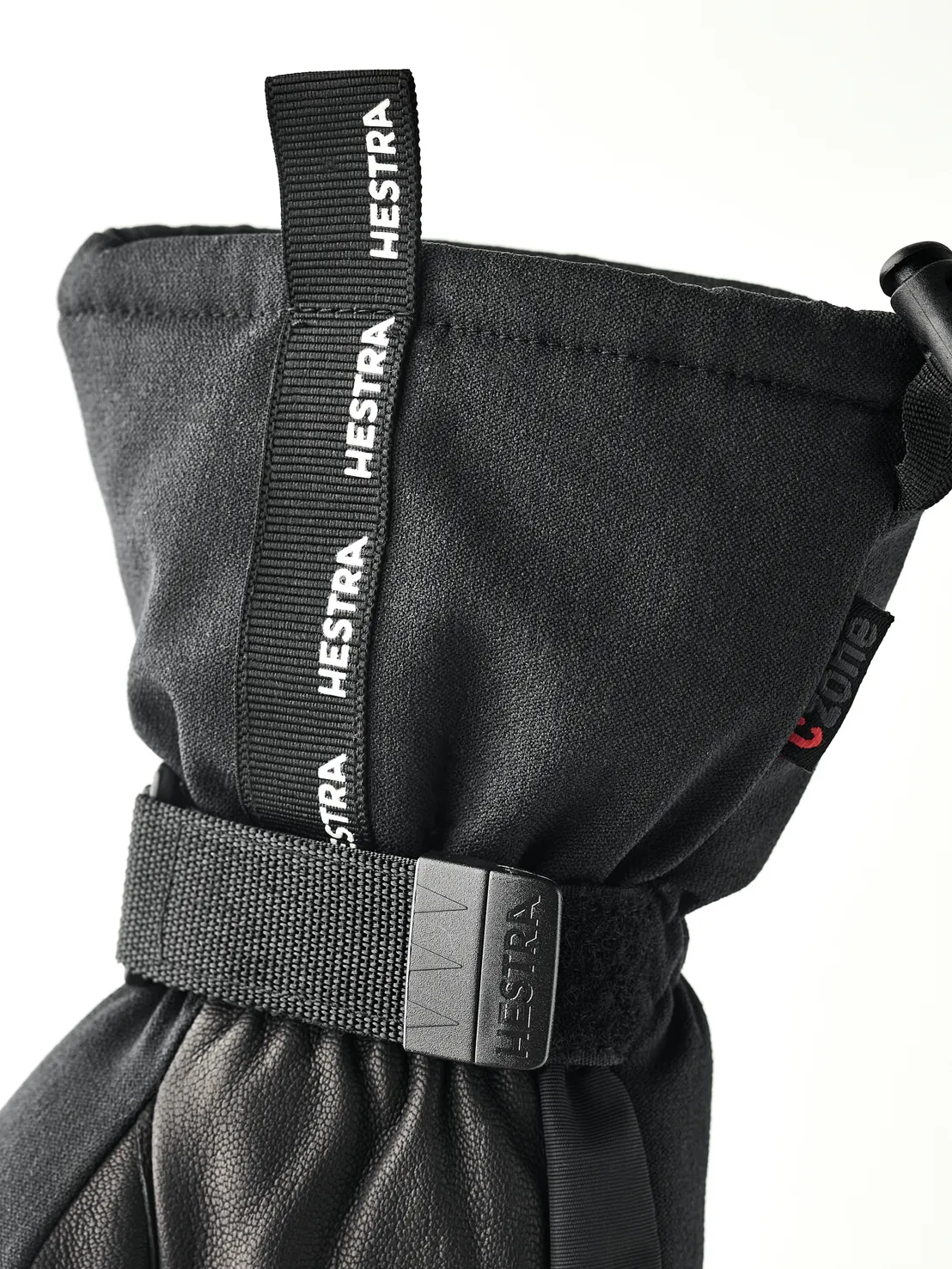 Gros plan sur un gant noir Hestra avec cordon de serrage et lanière ajustable.