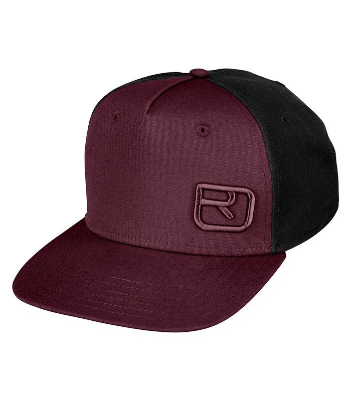 Wine red Ortovox cap with black side panels and flat peak, logo patch in the middle.