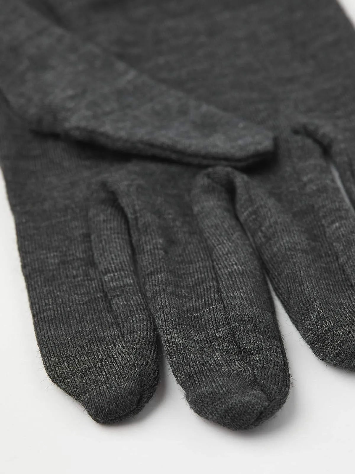 Close-up of a gray Hestra Merino Wool Liner Active glove. Textured knitting pattern visible.