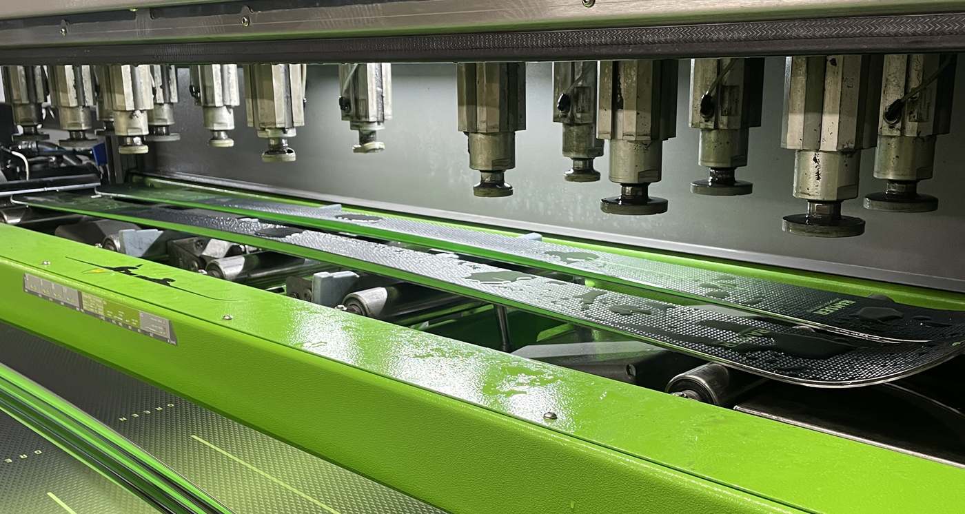 Ski laeuft in der Wintersteiger Mercury durch die Skiservice-Maschine in der Werkstatt von Ski-Shop Ramser