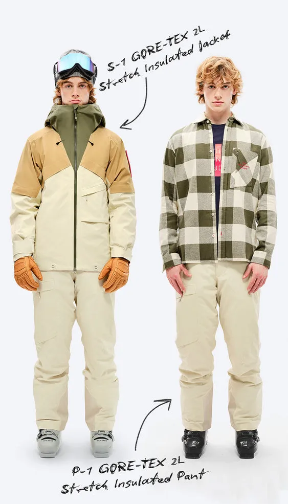 Due giovani uomini in piedi l'uno accanto all'altro, quello a sinistra in tenuta da sci, quello a destra in abiti quotidiani, entrambi con pantaloni beige su sfondo bianco.