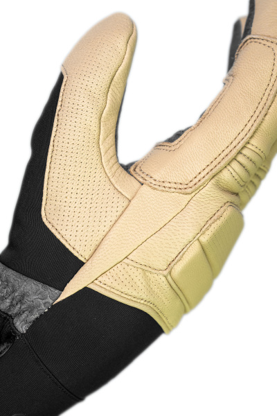 Nahaufnahme eines Handschuhs aus hellem Leder mit schwarzen Textilbereichen. Die Fingerkuppen sind perforiert. Steppnähte akzentuieren das Leder.