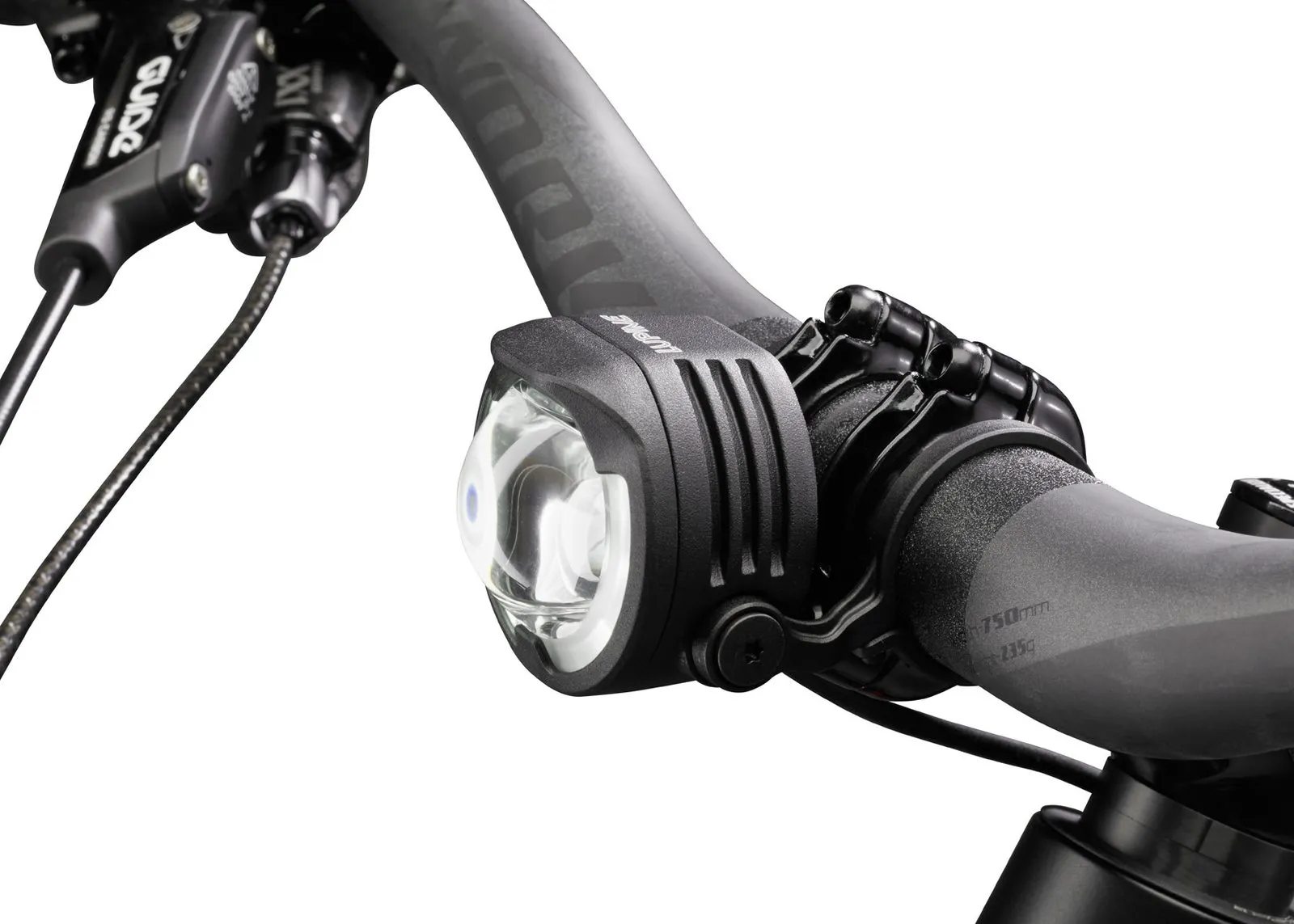 Nahaufnahme: Lupine E-Bike Beleuchtung am Fahrradlenker montiert. Die Lampe ist schwarz und hat ein klares Glas.