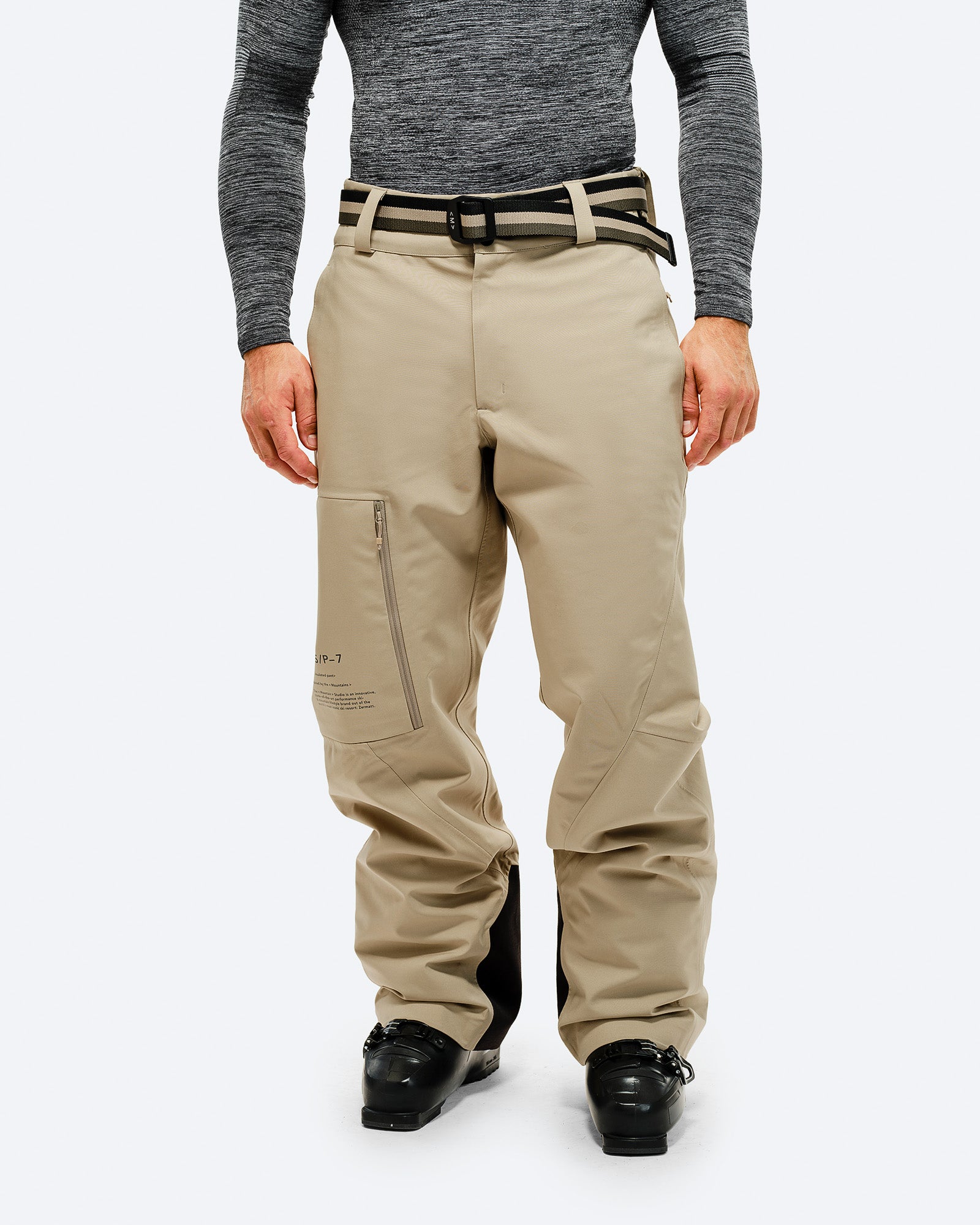 Personne portant un pantalon vert forêt et une ceinture, debout sur un fond blanc.