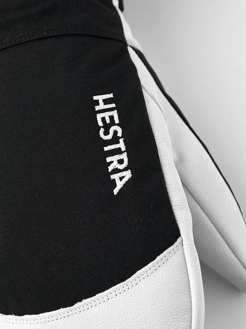 Gros plan sur un gant noir Hestra avec du cuir blanc et l'inscription blanche "HESTRA" sur le dessus.