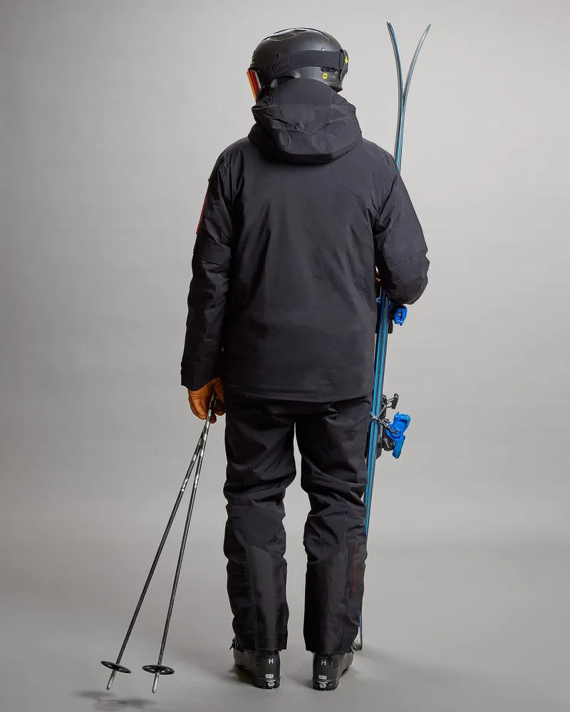 Person von hinten mit Ski, Stöcken, Helm und schwarzer S-1 Gore Tex 2L Stretch Insulated Jacke und Hose.