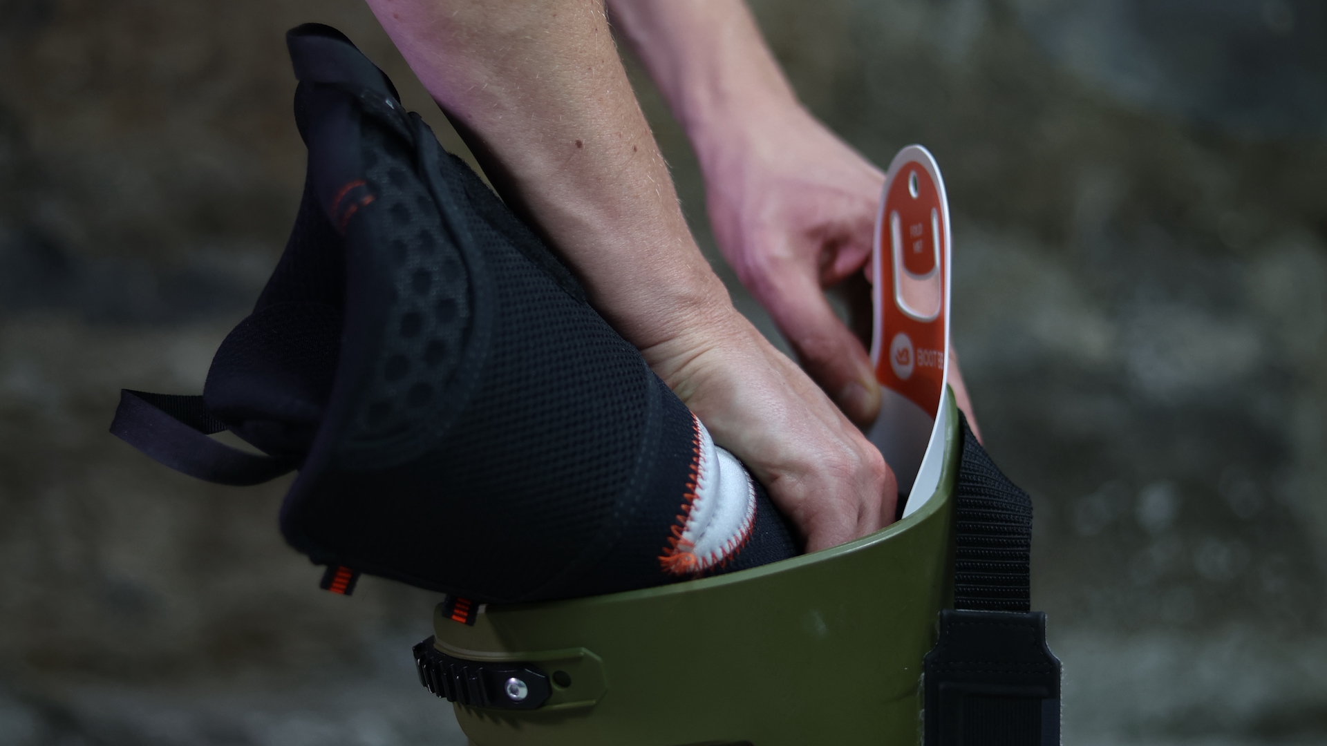 Nahaufnahme von Händen, die einen Save Liner in einen grünen Boot stecken. Der Liner ist schwarz mit weißen Details.
