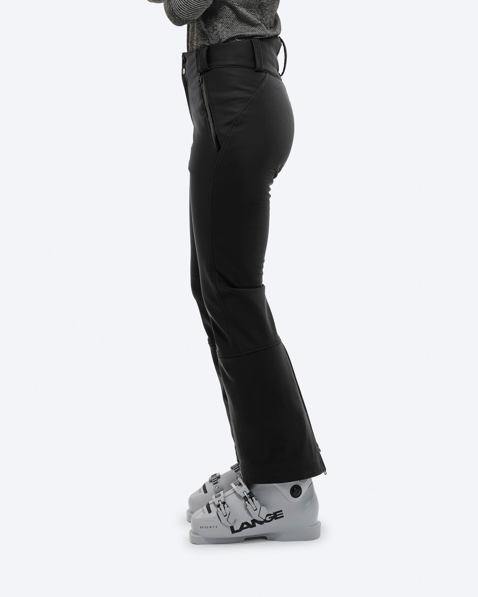 Black stretch ski pants Profile view: Black stretch ski pants with ski boots. Zipper detail on the leg.