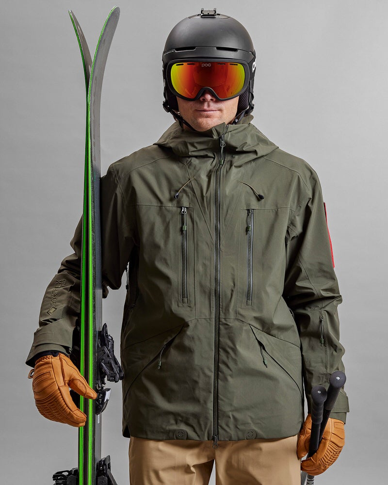 Grüne GORE-TEX Jacke Person mit Ski, Helm und Brille trägt eine grüne Z-2 HD GORE-TEX Pro 3L Shell Jacket.