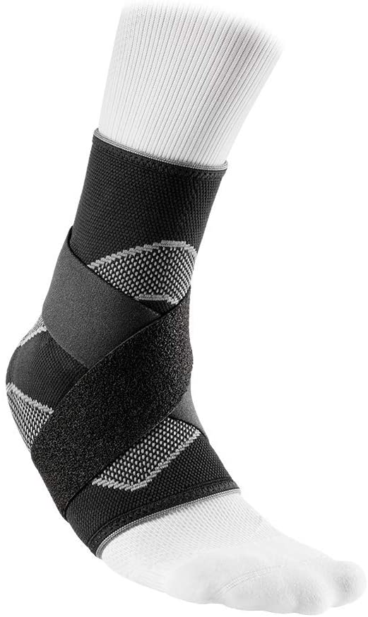 Bandage de cheville, noir avec sangles d'enveloppement, enfilé sur une chaussette blanche sur une jambe.