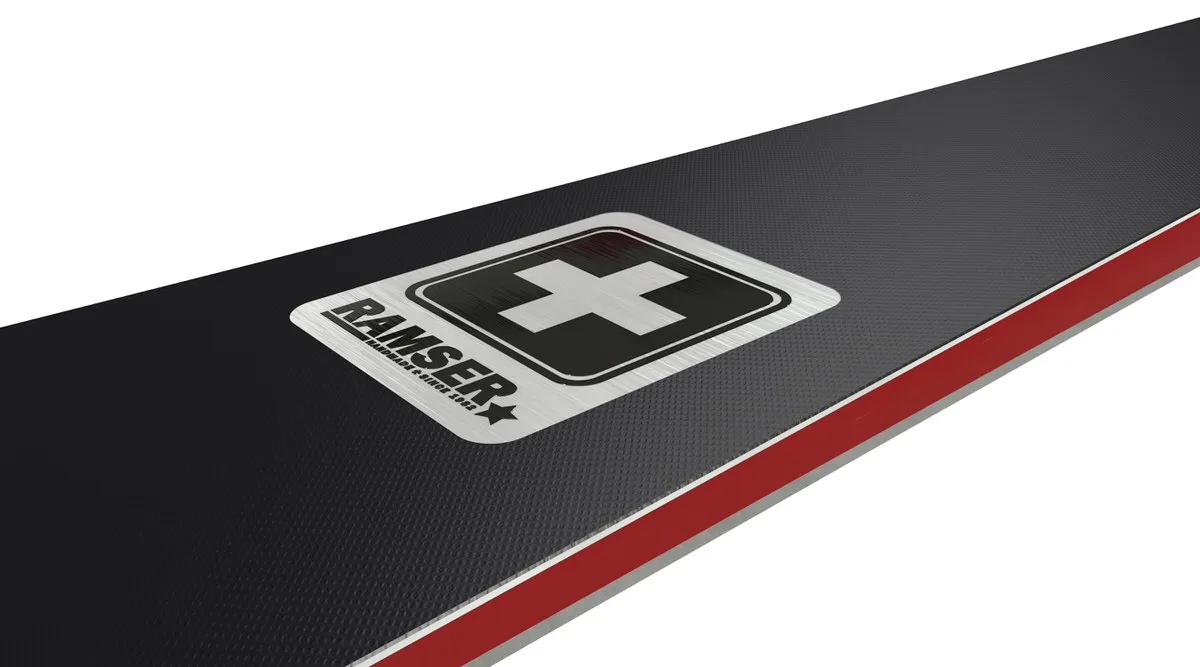 Detailansicht vom Ski mit Ramser Logo und Schweizer Kreuz auf schwarzem Hintergrund mit rotem Rand.