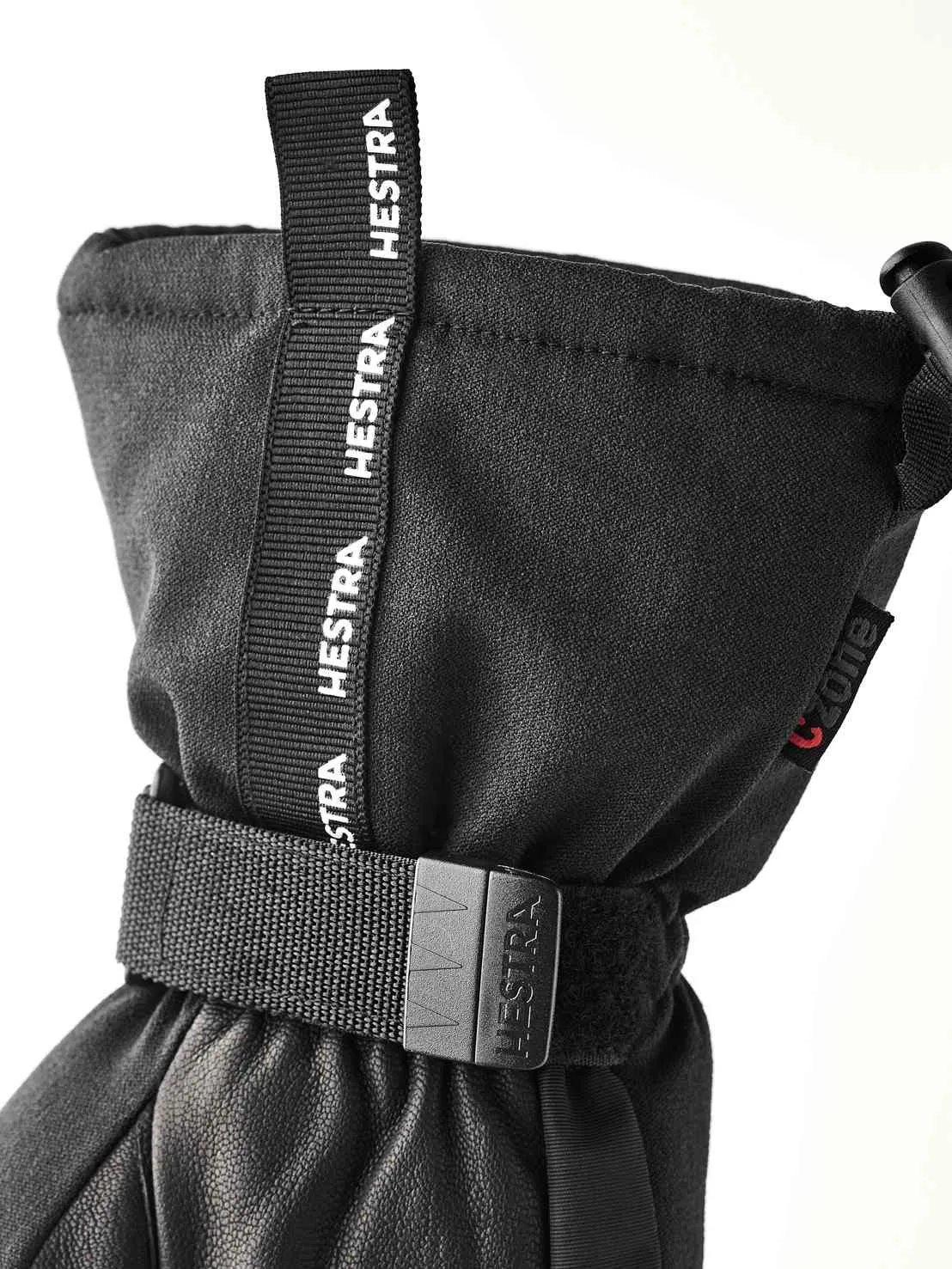 Gros plan sur un gant noir Hestra avec cordon de serrage et lanière ajustable.