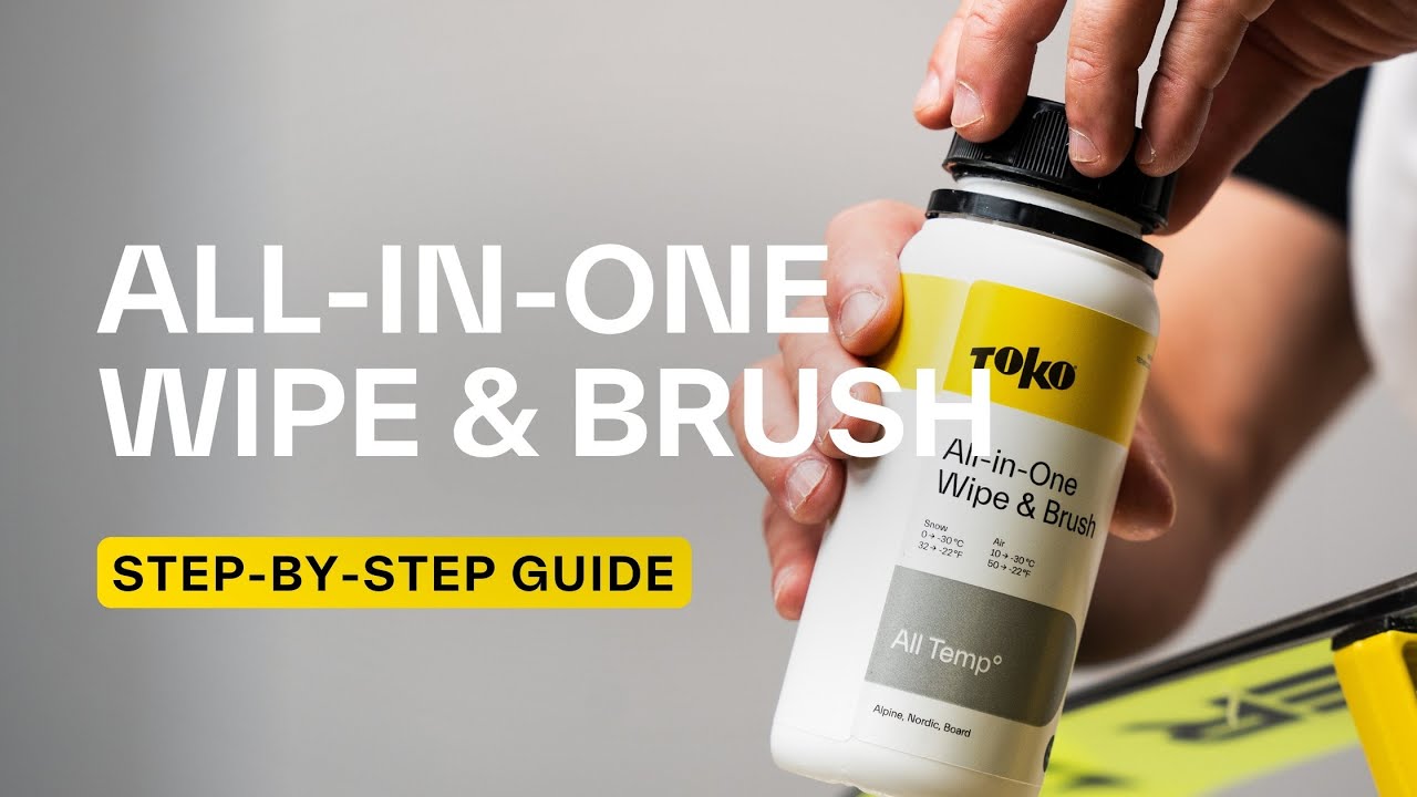 Une main tient un flacon "Toko All-in-One Wipe & Brush". Sur la bouteille figurent des indications de température pour la neige et l'air.
