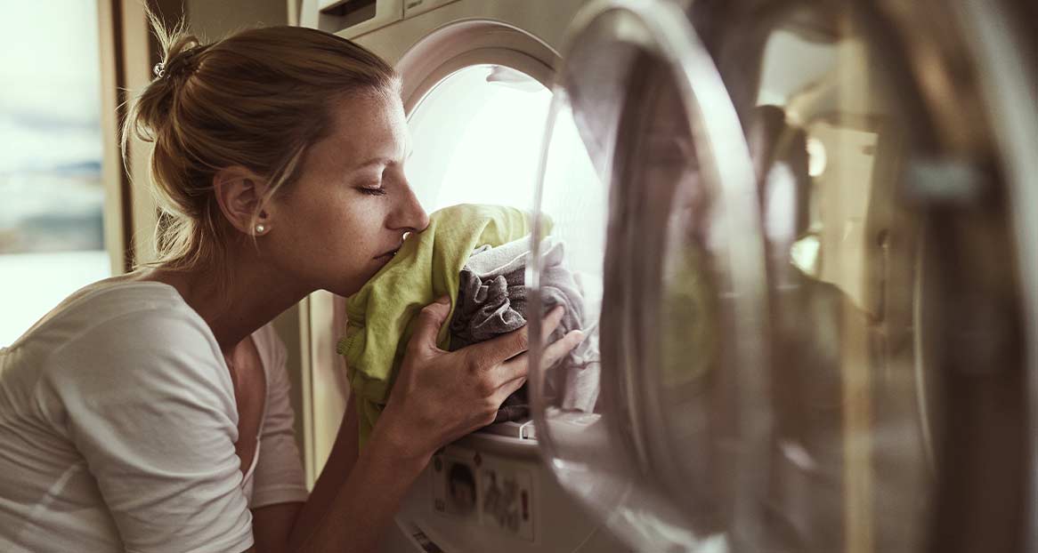 Frisch gewaschene Wäsche Eine Frau riecht an frisch gewaschener Wäsche, die sie aus einer Waschmaschine nimmt.