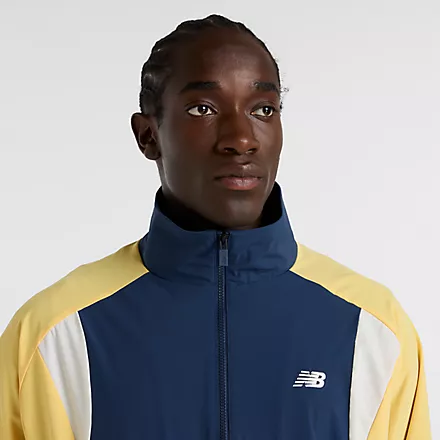 New Balance Track Jacket Nahaufnahme einer New Balance Track Jacket in Navy, Gelb und Weiß mit Reißverschluss und NB-Logo.