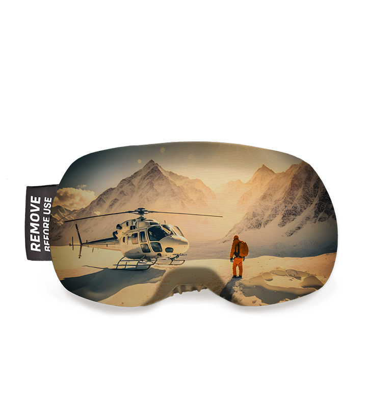 Skibrillenschutz mit Heli-Motiv: Helikopter vor Bergkulisse, eine Person im Schnee.