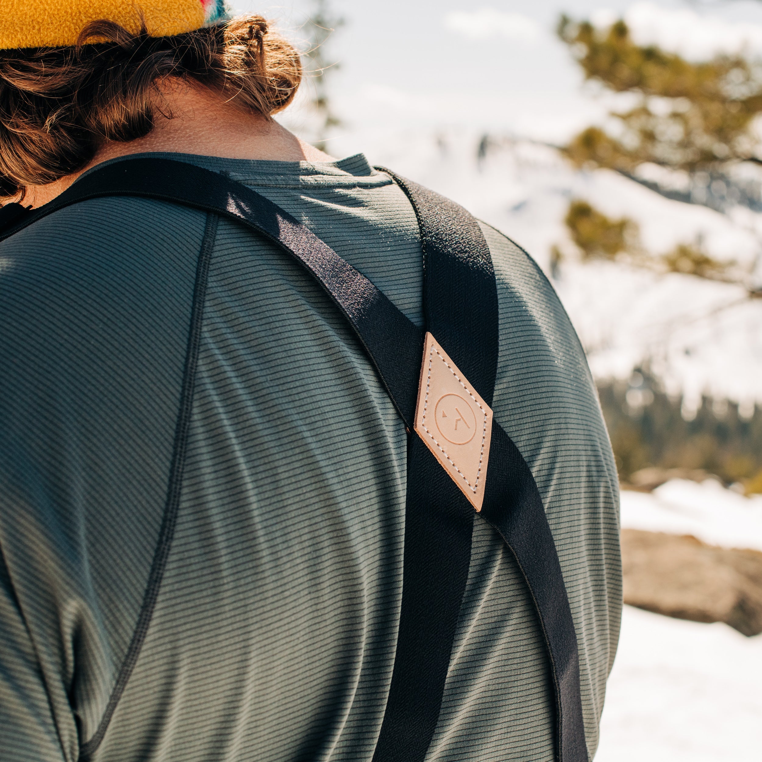 Schwarze Hosenträger mit Leder Schwarze Hosenträger mit Lederdetail auf einem Mann mit gestreiftem Shirt vor verschwommenem Hintergrund.