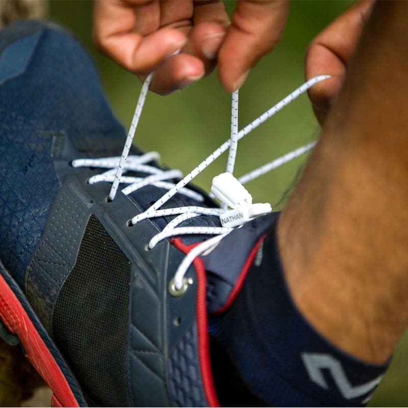 Schnürsenkel mit Clip Nahaufnahme: Person bindet Run Laces an einem Laufschuh. Weiße Schnürsenkel mit Clip.