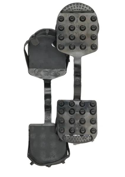 Black Cat Tracks ski boot soles with studs for better traction on ice, connected by a strap.