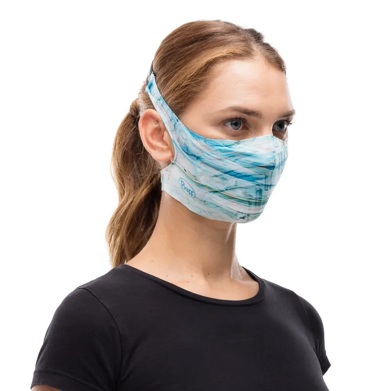 Une femme porte un masque à filtre bleu clair et blanc Buff. Le masque a un ciel abstraitLook.