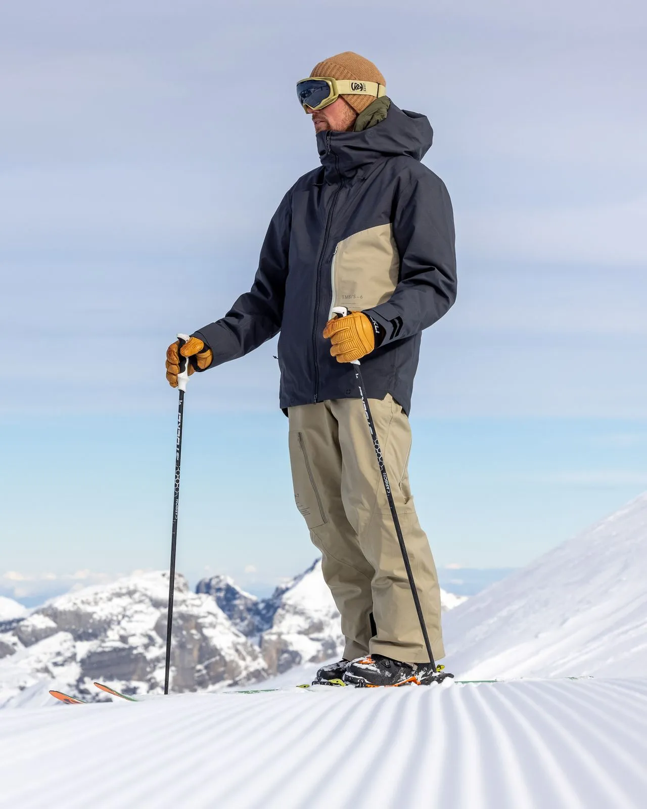 Skier in P-7 Ride Insulated Pant Seneca Rock, with cap, goggles and ski poles on a groomed slope.