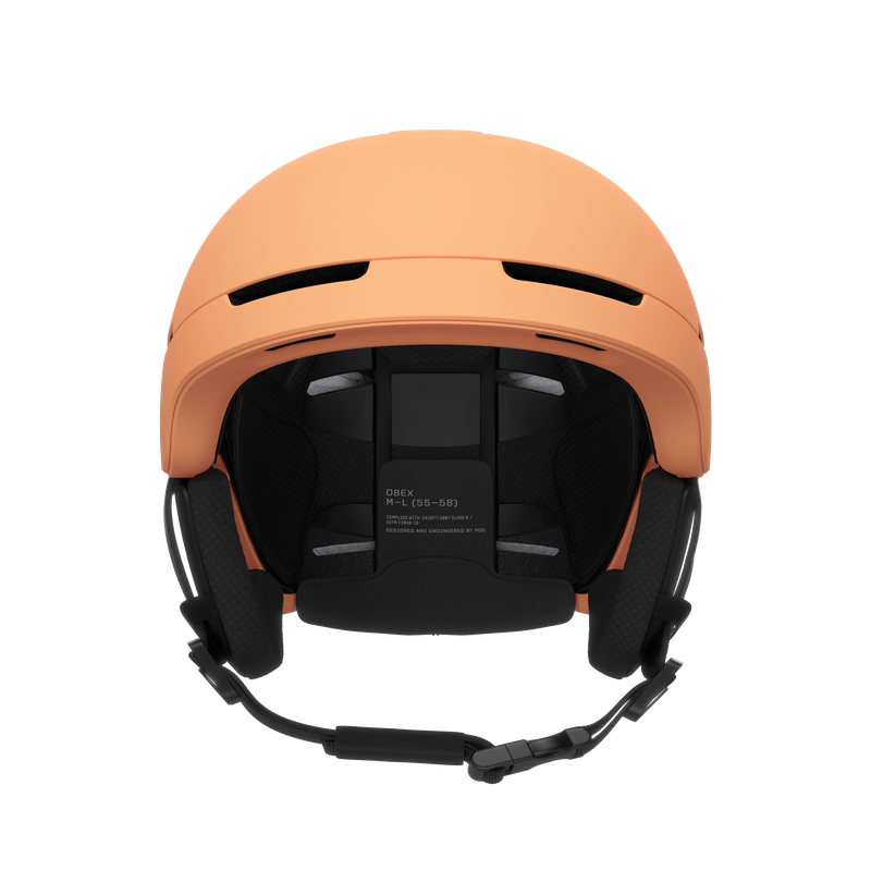 Pfirsichfarbener Skihelm von vorne, Kinnriemen und Ohrenschützer sind sichtbar.