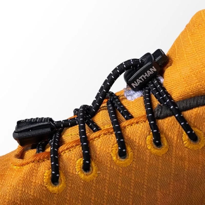 Detailed view of a yellow shoe with black run laces fastened with a black fastener with the "Nathan" logo.