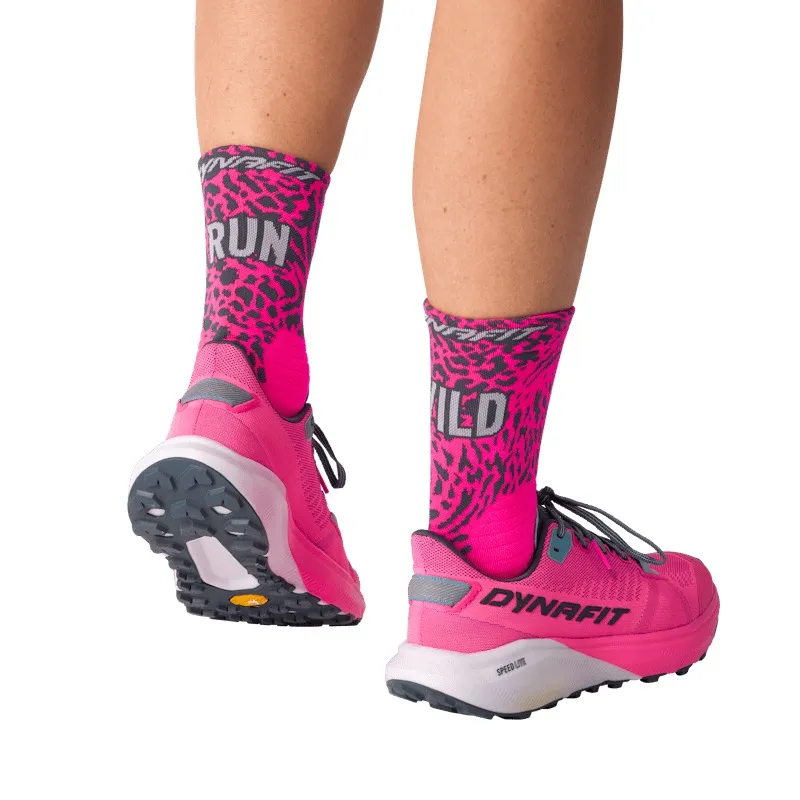 Two legs wear pink running shoes and socks with the print "RUN WILD" in a leopard pattern.