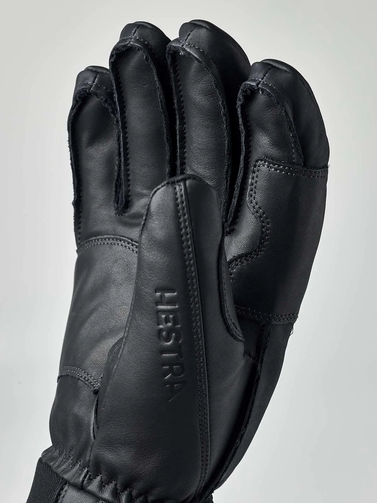 Schwarzer Hestra Fall Line Lederhandschuh aus Rindsleder, Handfläche mit eingeprägtem Schriftzug Hestra im Detail.