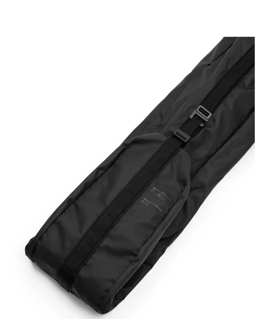 Black, filled Douchbag Snow Essential ski bag, diagonal in the picture, with carrying strap and "Db" and "220" print.
