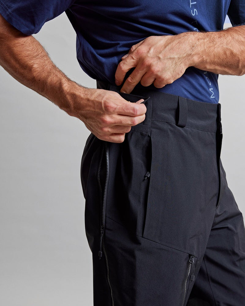 Schwarze GORE-TEX Shell-Hose Detailaufnahme der schwarzen Y-1 HD GORE-TEX Pro 3L Shell Pant. Die Hose hat eine Tasche und einen Reißverschluss.