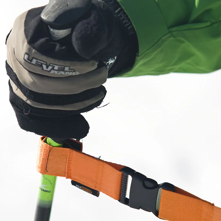 Close-up of hand with glove on the handle of a ski pole with orange training strap.