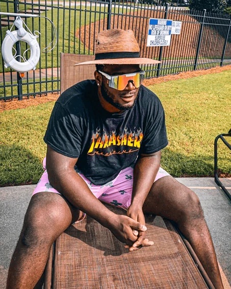 Mann mit Hut und Sonnenbrille "Miami Nights" sitzt am Pool.