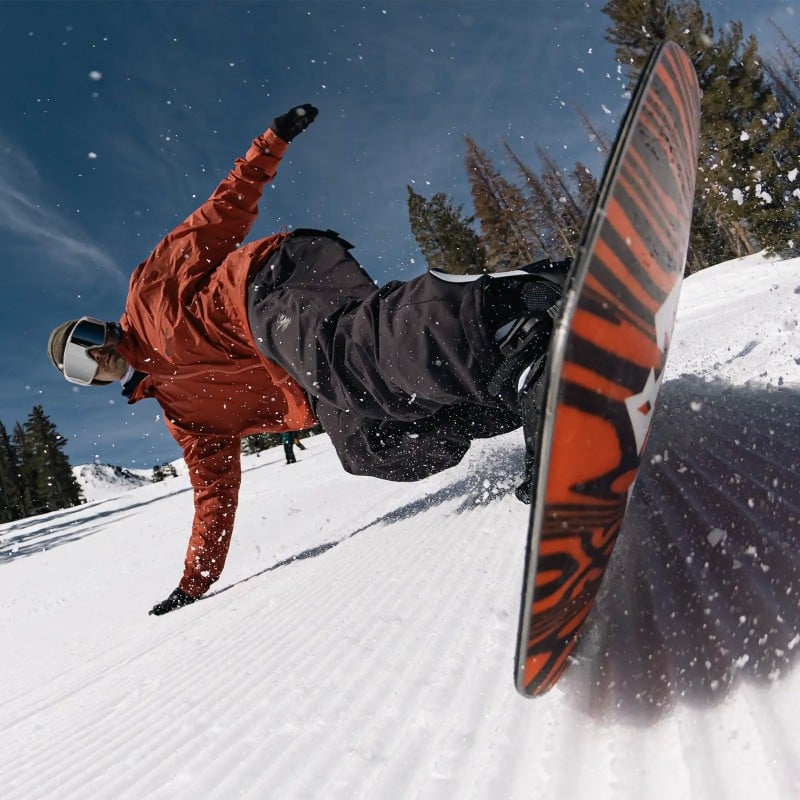 Freecarver 9000s Action Snowboarder fährt Freecarver 9000s auf präparierter Piste mit seitlicher Handberührung, Fokus auf Boardkante.