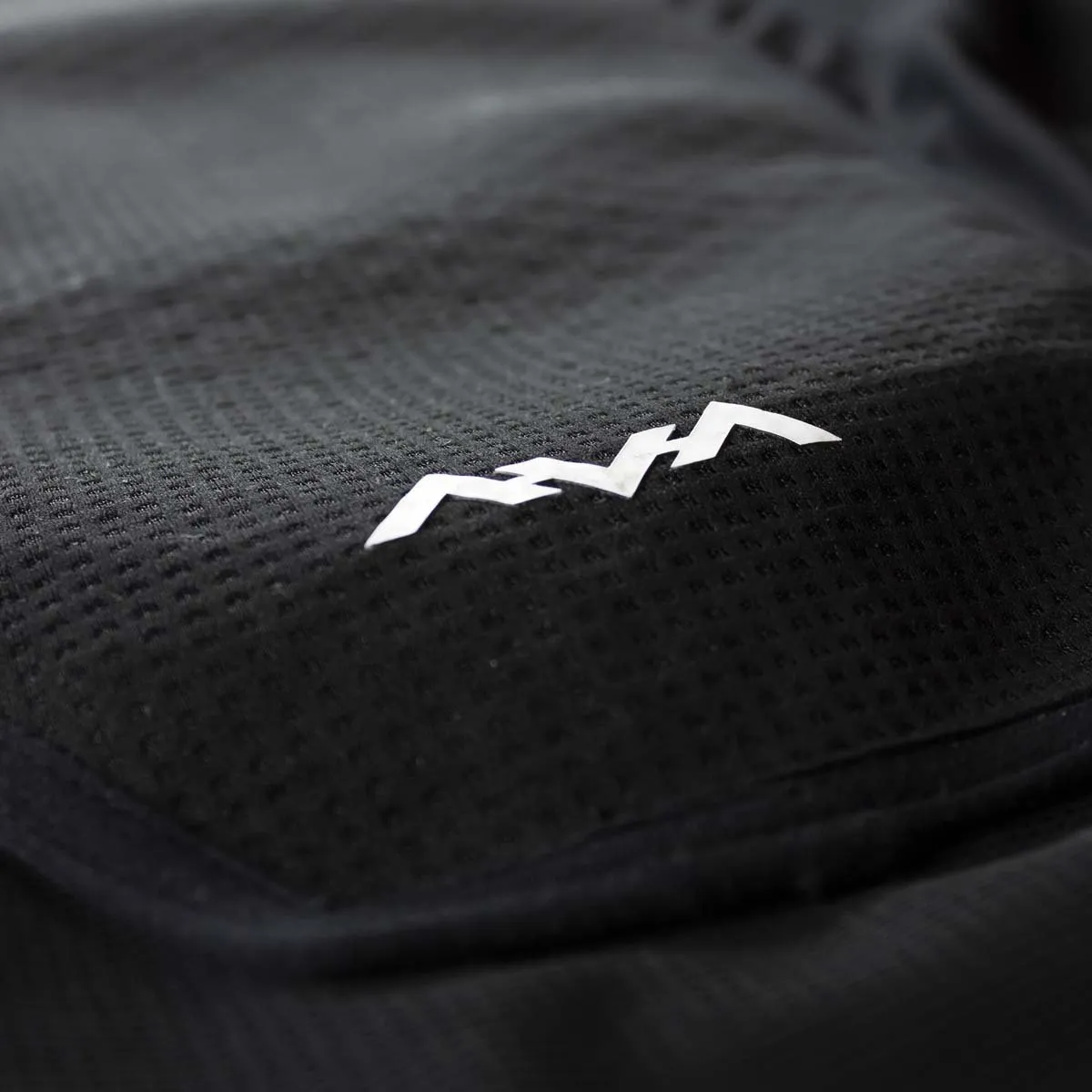 Close-up of the Behold Junior vest: Black, breathable fabric with white Berg logo.