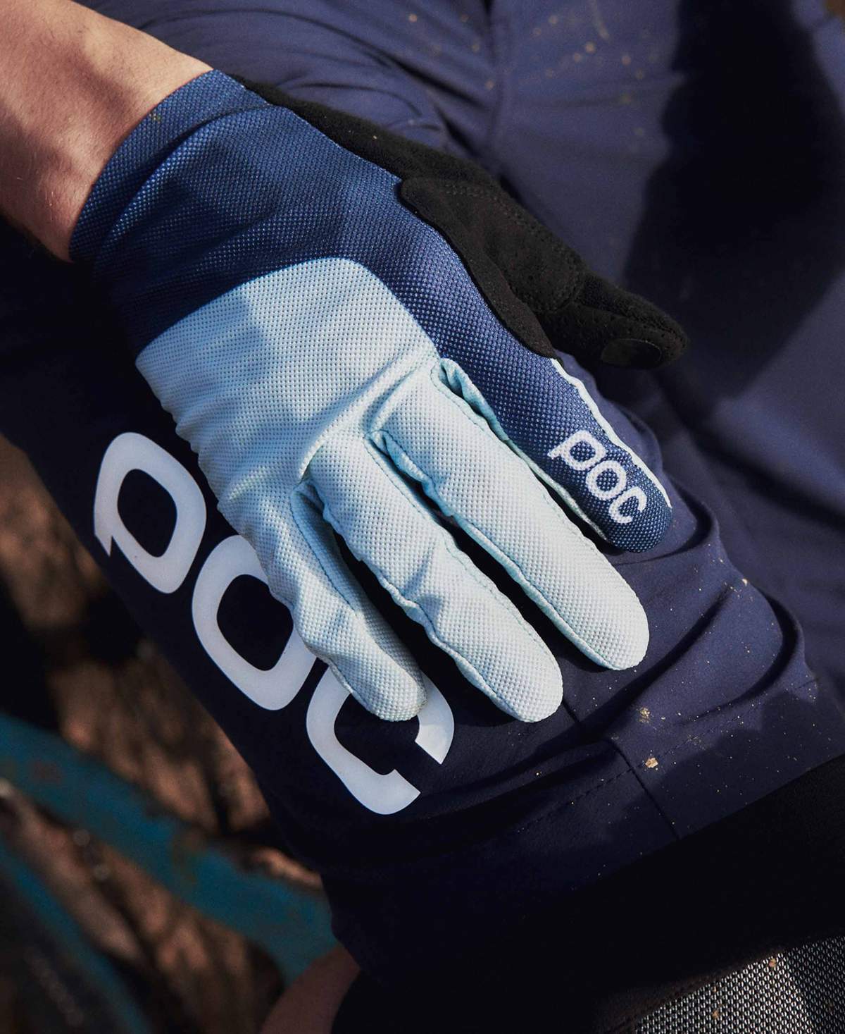 Nahaufnahme eines Mesh Glove Navy, der auf einem Bein mit POC-Logo liegt. Der Handschuh ist hellblau und dunkelblau.